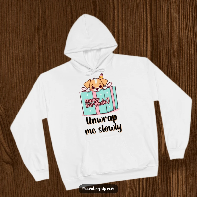 Funny hoodie with a puppy playfully peeking out from a giant birthday gift box, offering cozy surprise.
