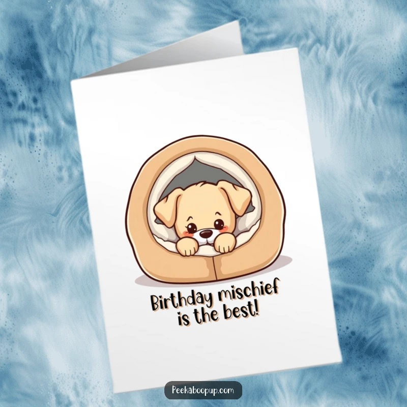 Free Printable Birthday Card: Adorable puppy peeking slyly from a comfy dog bed, plotting birthday mischief. Cute and funny.